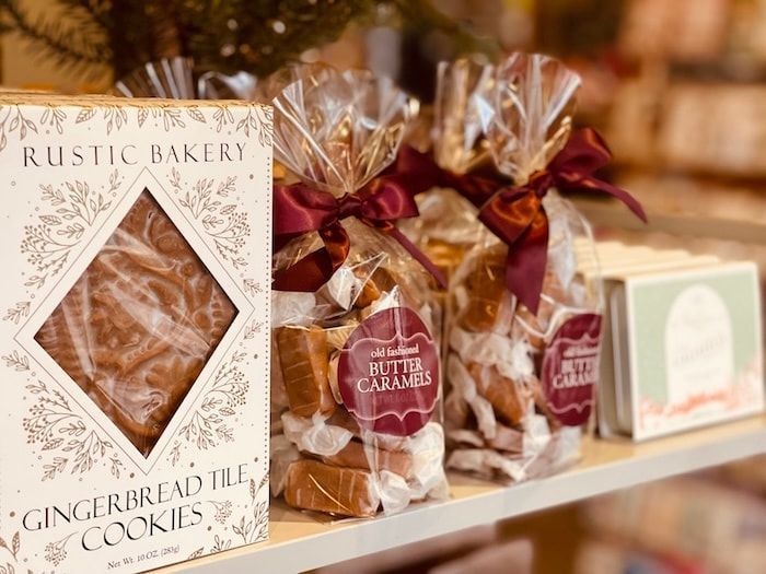Gift bags of rustic gingerbread cookies on a bakery shelf, with a boxed cookie package in front