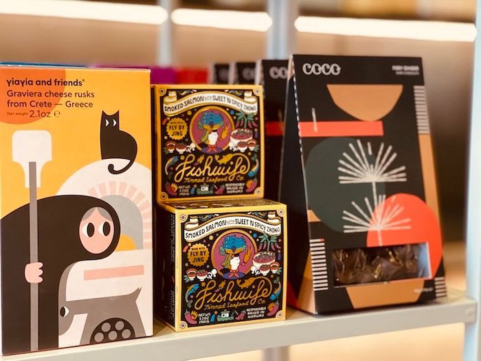 Shelf display of colorful packaged goods with stylized illustrations and black-and-orange designs