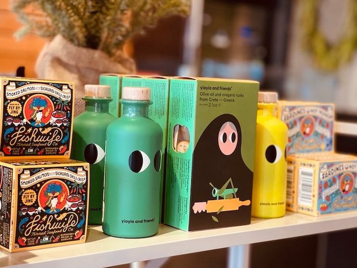 Colorful packaged bottles on a shelf, including green, black, and yellow containers with cartoon faces.