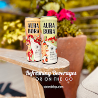 Two Aura Bora cans on a patio table with flowers and text, “Refreshing Beverages For On The Go”