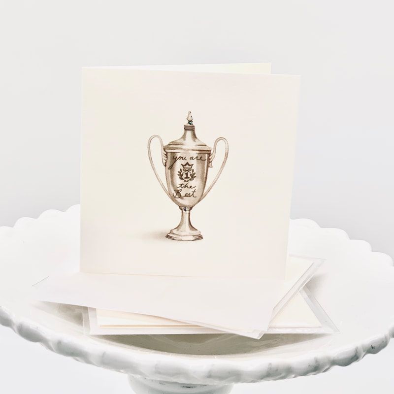 A silver trophy printed on a cream card, stacked on a white scalloped plate.