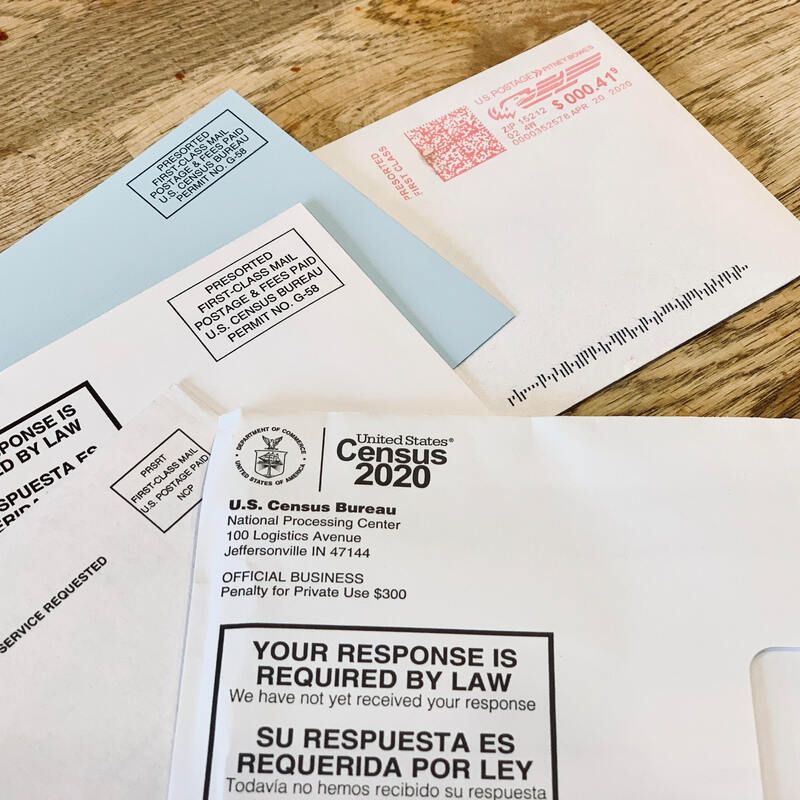 U.S. Census 2020 mailers with response-required notices and QR codes on a table