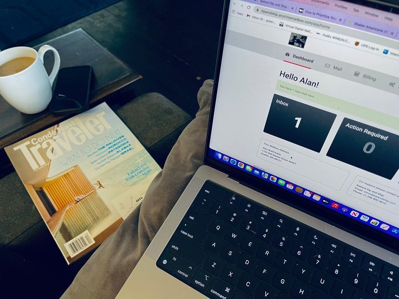 Laptop on a couch beside a coffee cup and magazine, showing a website dashboard.