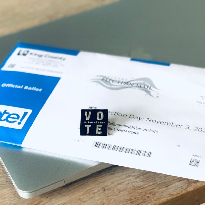 Vote-by-mail envelope and ballot on a laptop, with a black “VOTE” sticker on top