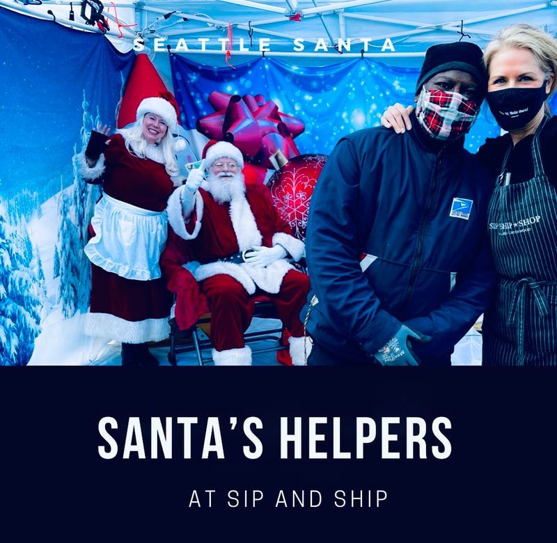 Holiday display with Santa and helpers posing under a Seattle Santa tent, “Santa’s Helpers” text below