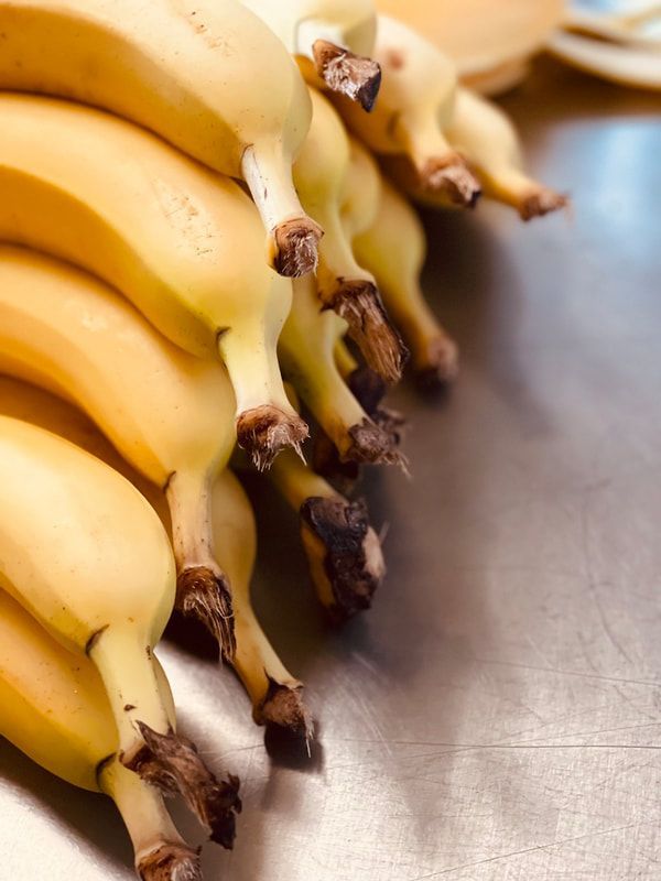 A bunch of ripe yellow bananas with brown tips on a metal surface