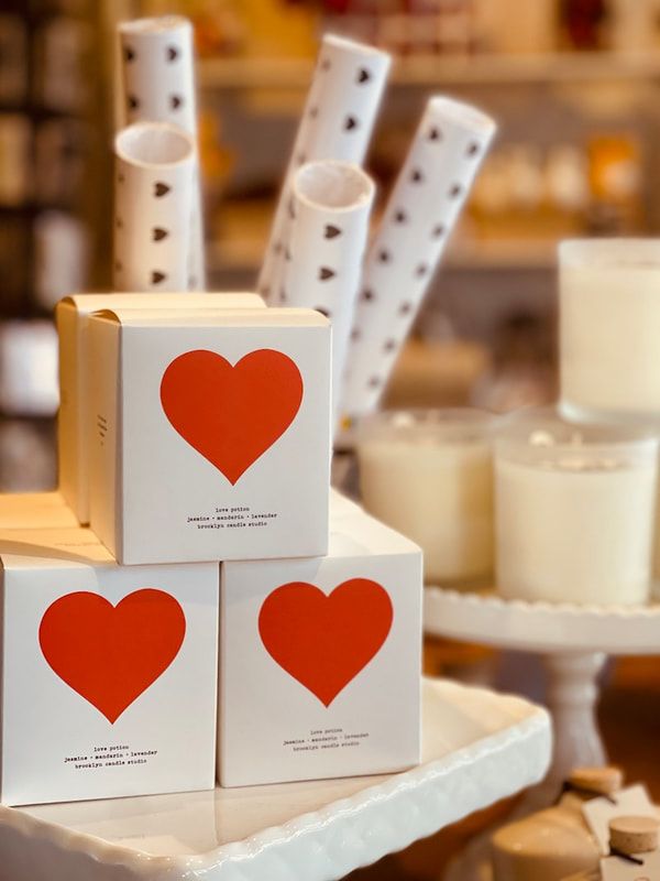White gift boxes with red hearts displayed among candles on a dessert table