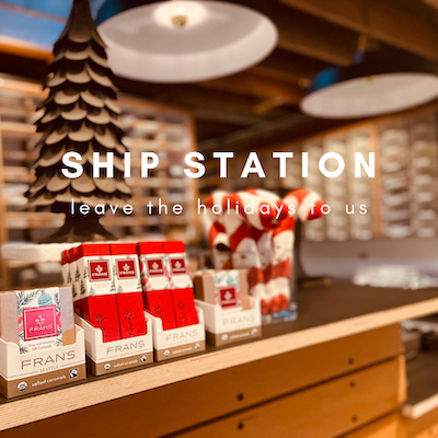 Holiday shop display with red and white gift boxes on a counter and “SHIP STATION” text overlay
