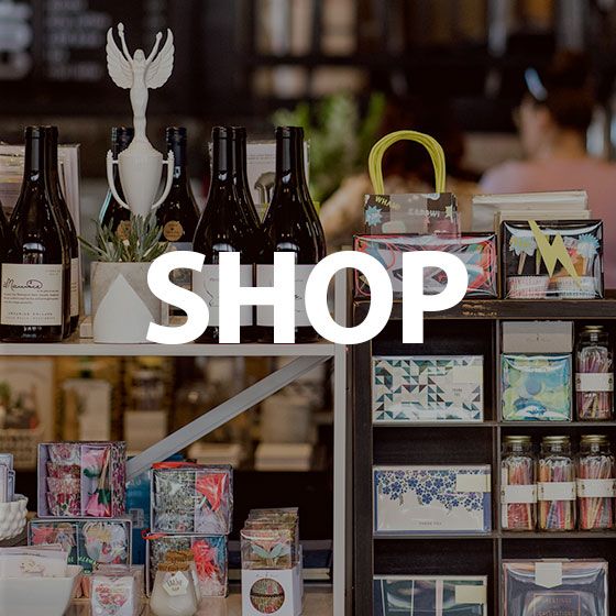 Shop display with wine bottles, gift boxes, and decorative jars on shelves, with “SHOP” text overlayed