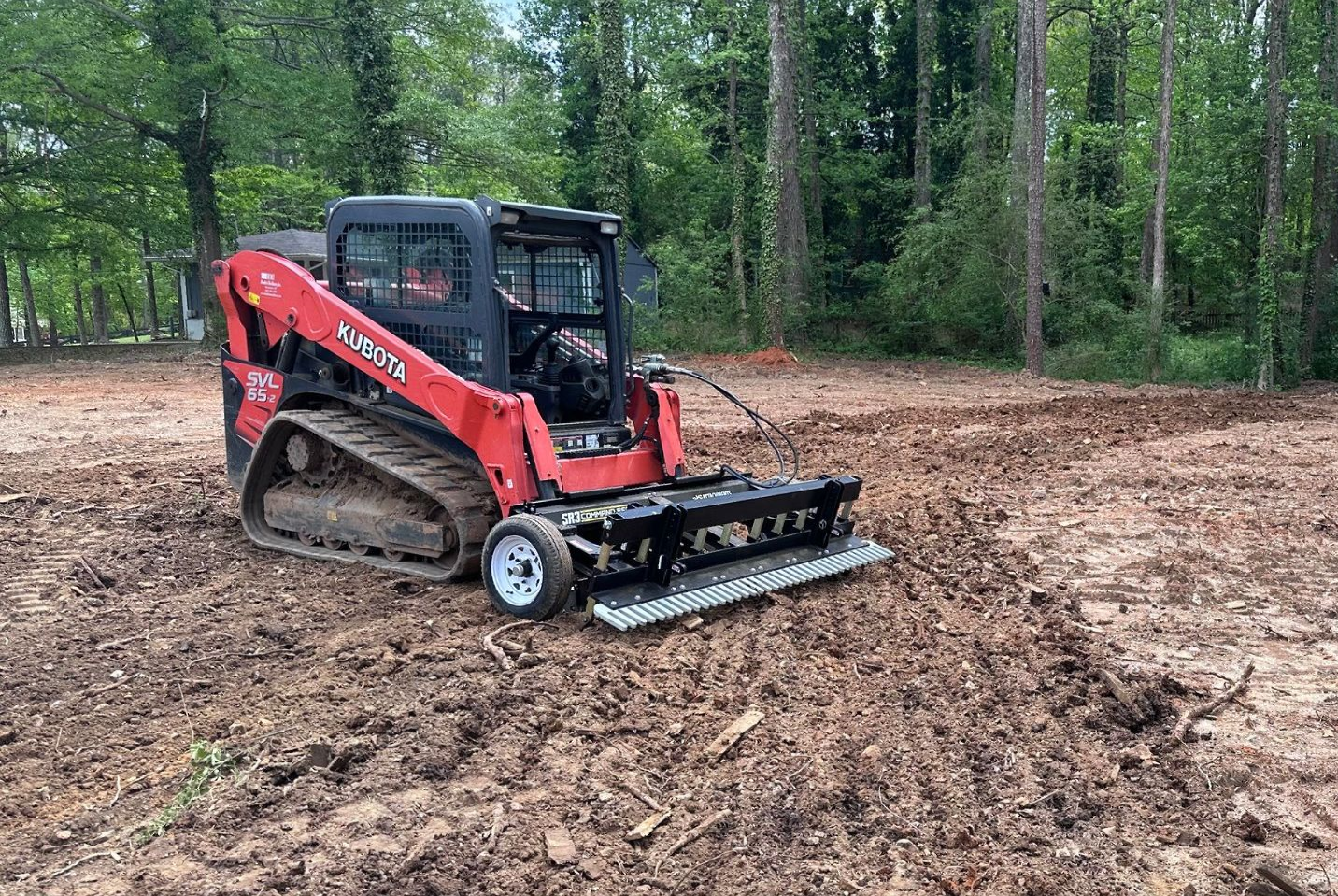 A red bulldozer is driving through a dirt field.