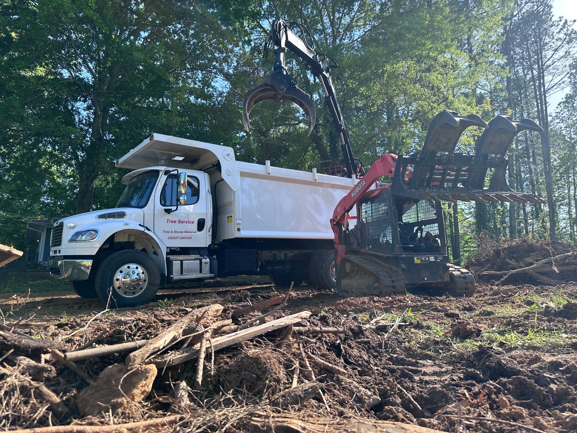 A dump truck with a crane attached to it is driving through a pile of wood.