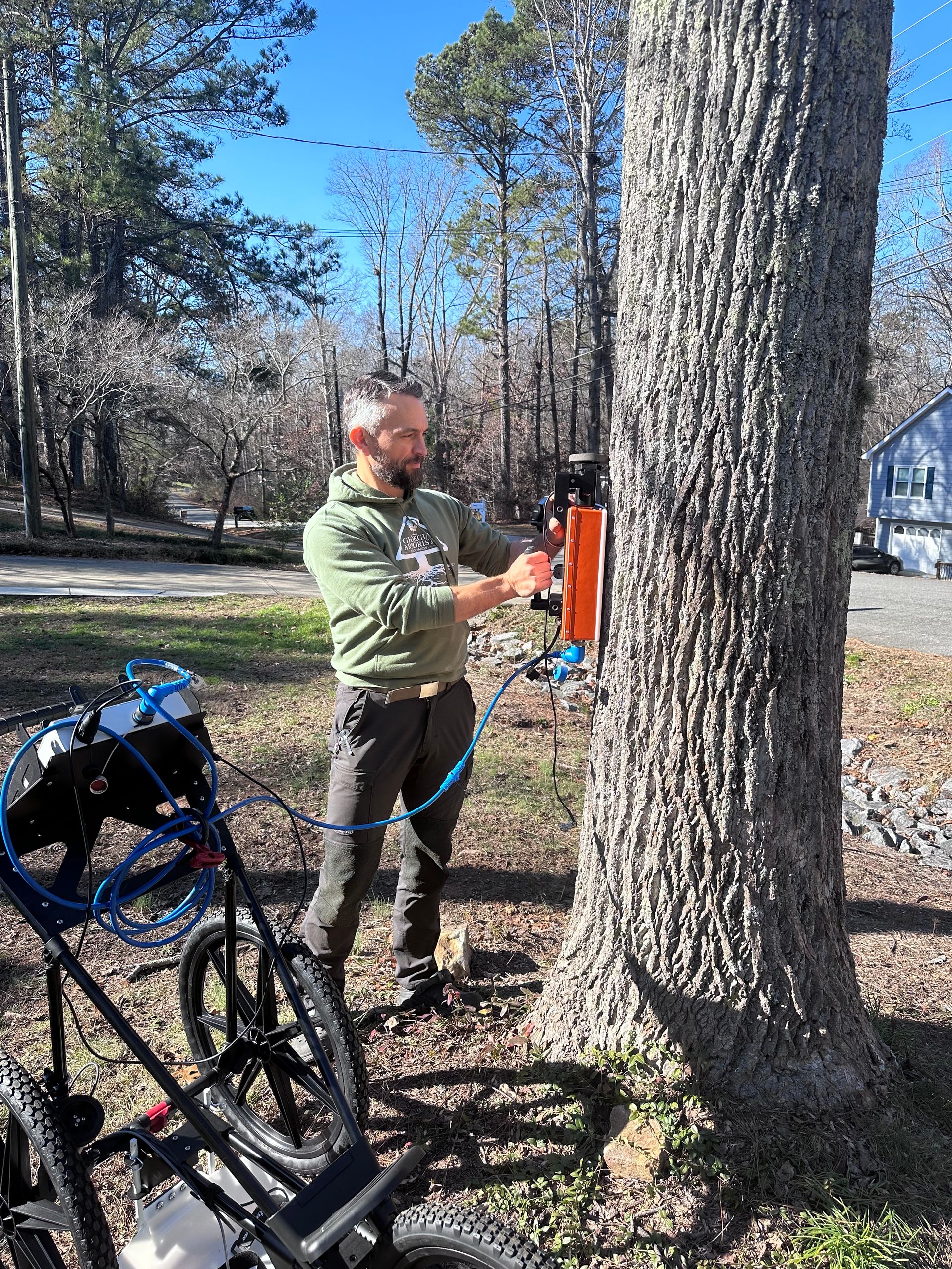 A man is standing next to a tree holding a rope.