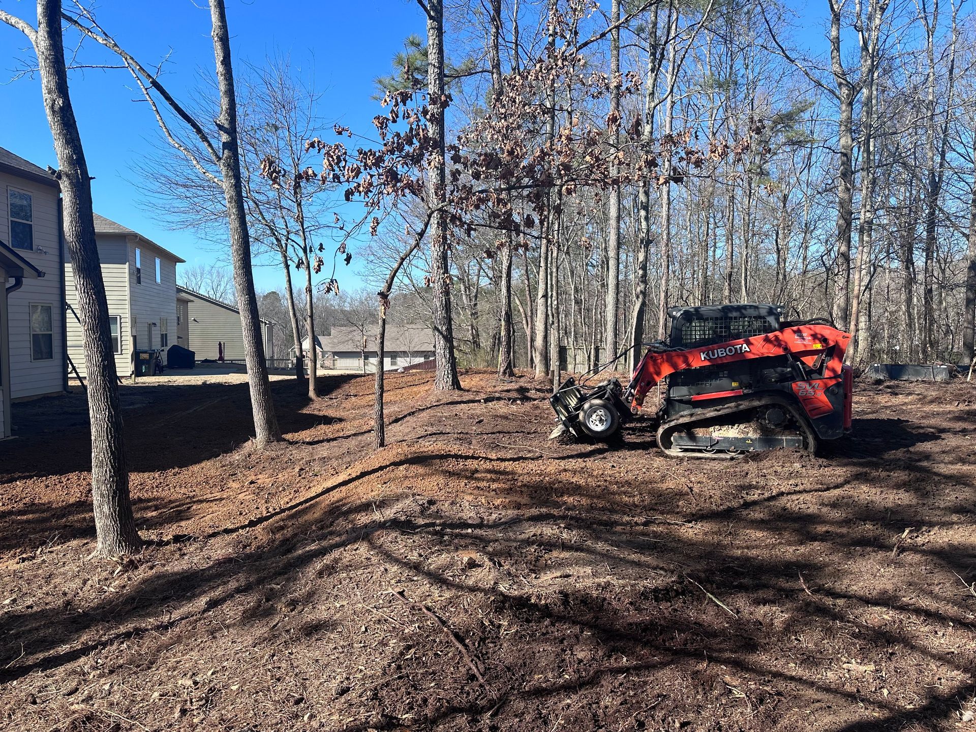 A red bulldozer is parked in the middle of a forest.