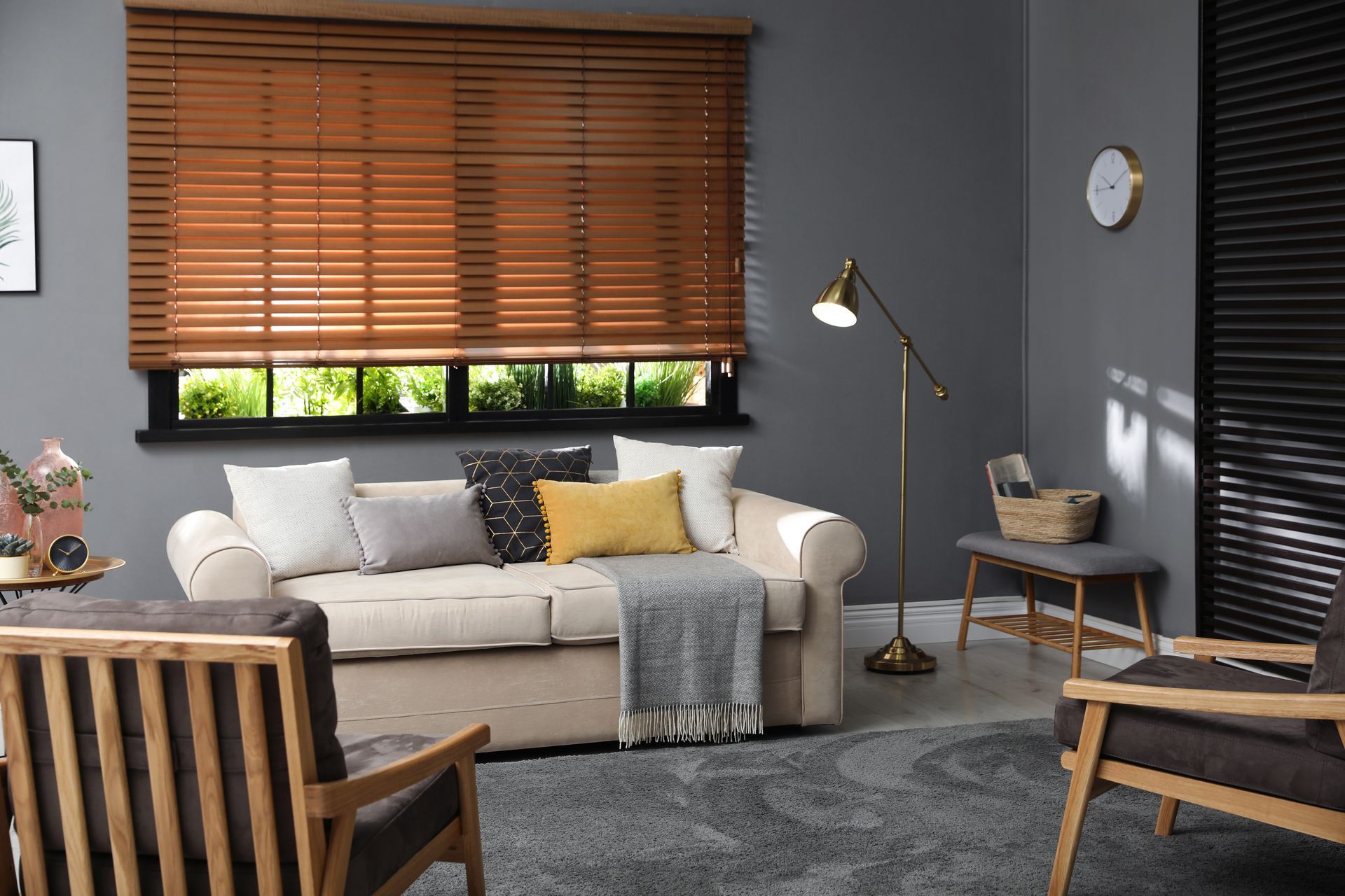 Cozy living room with beige sofa, wooden blinds, floor lamp, gray rug, and accent chairs