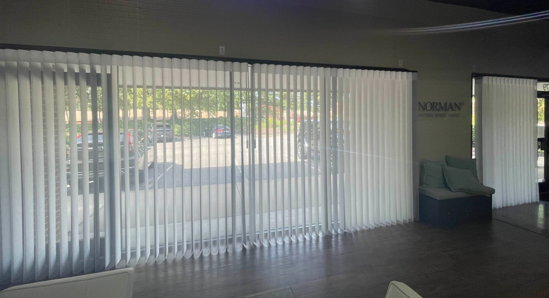 Showroom with tall vertical Norman SmartDrapes covering a bright window and a blue sofa by the wall