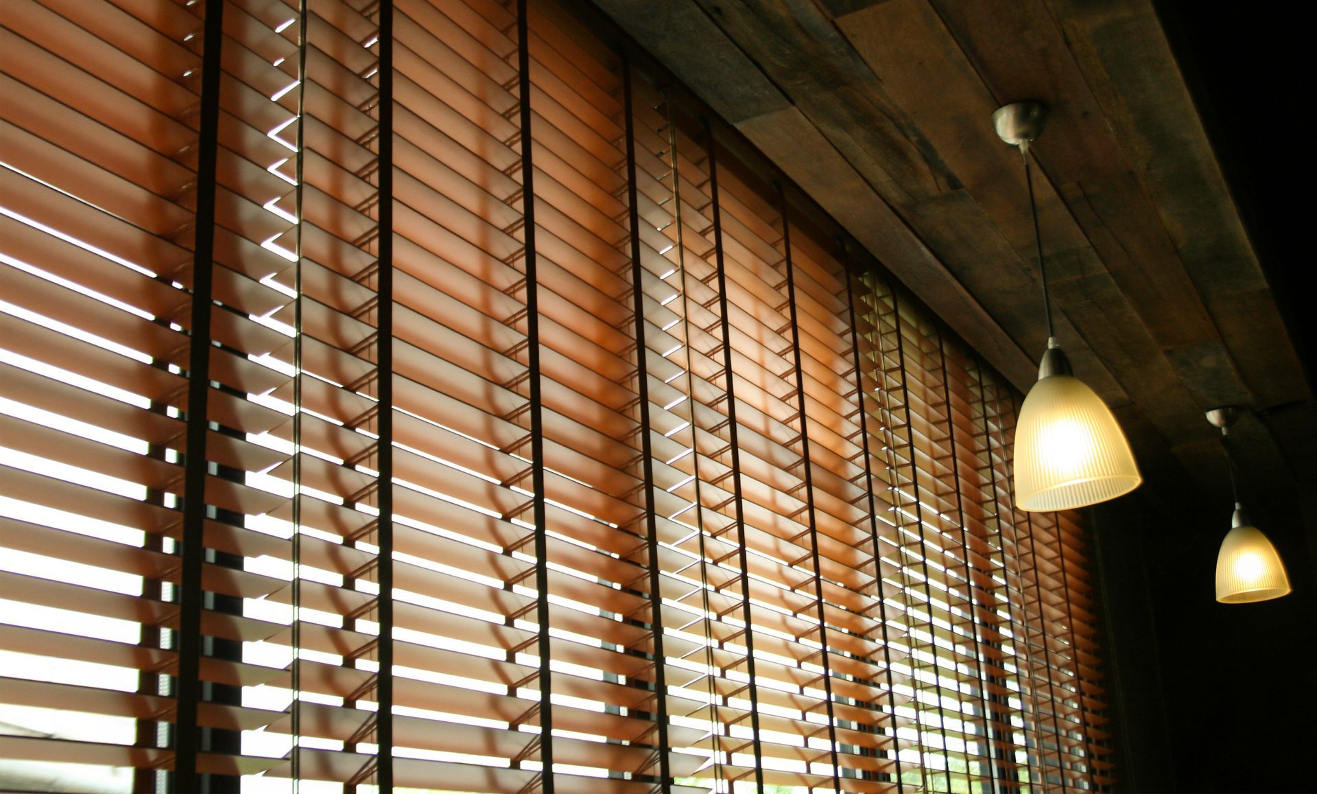 Wooden blinds beside warm pendant lights in a dimly lit interior room