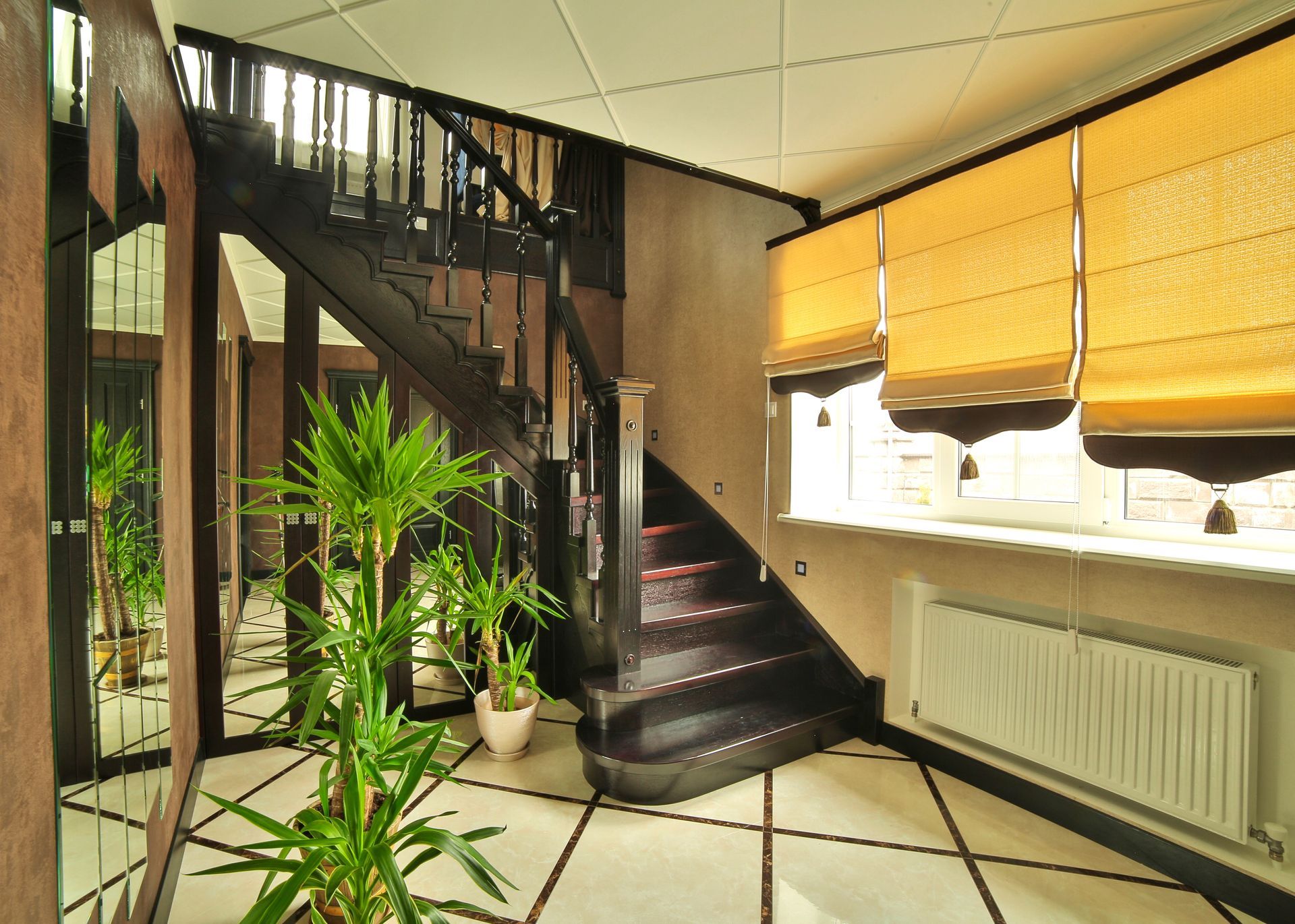 Indoor stairway with potted plants, dark wood stairs, tiled floor, and sunlit windows with blinds