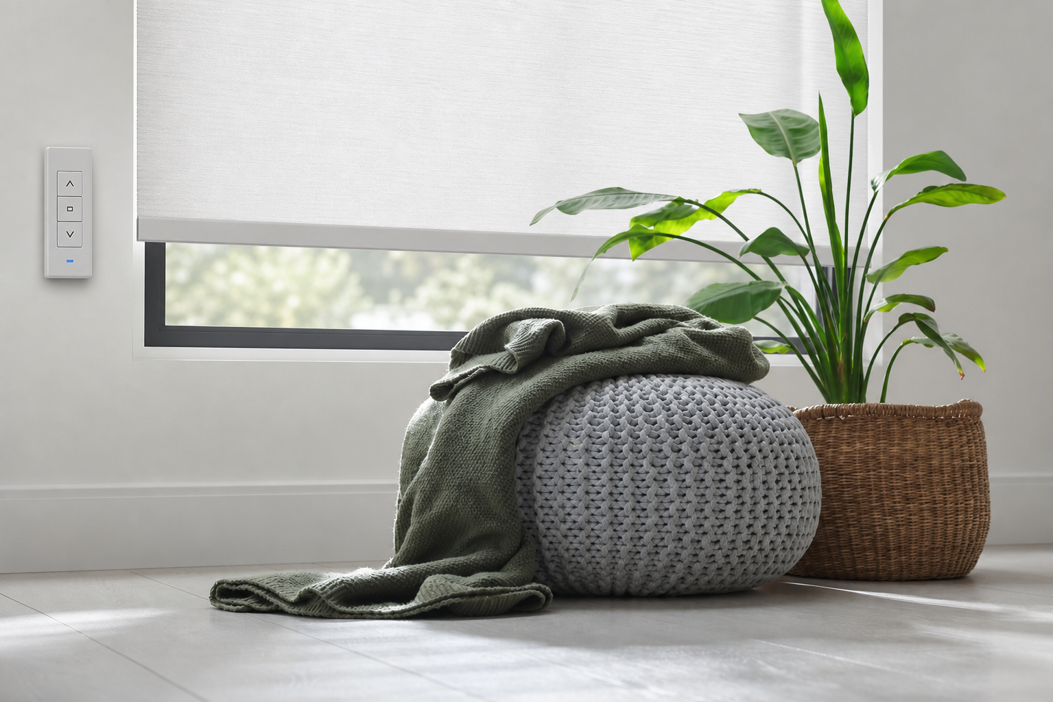 Cozy gray ottoman with green throw beside a wicker basket plant under a window shade Cozy gray ottoman with green throw beside a wicker basket plant under a window shade