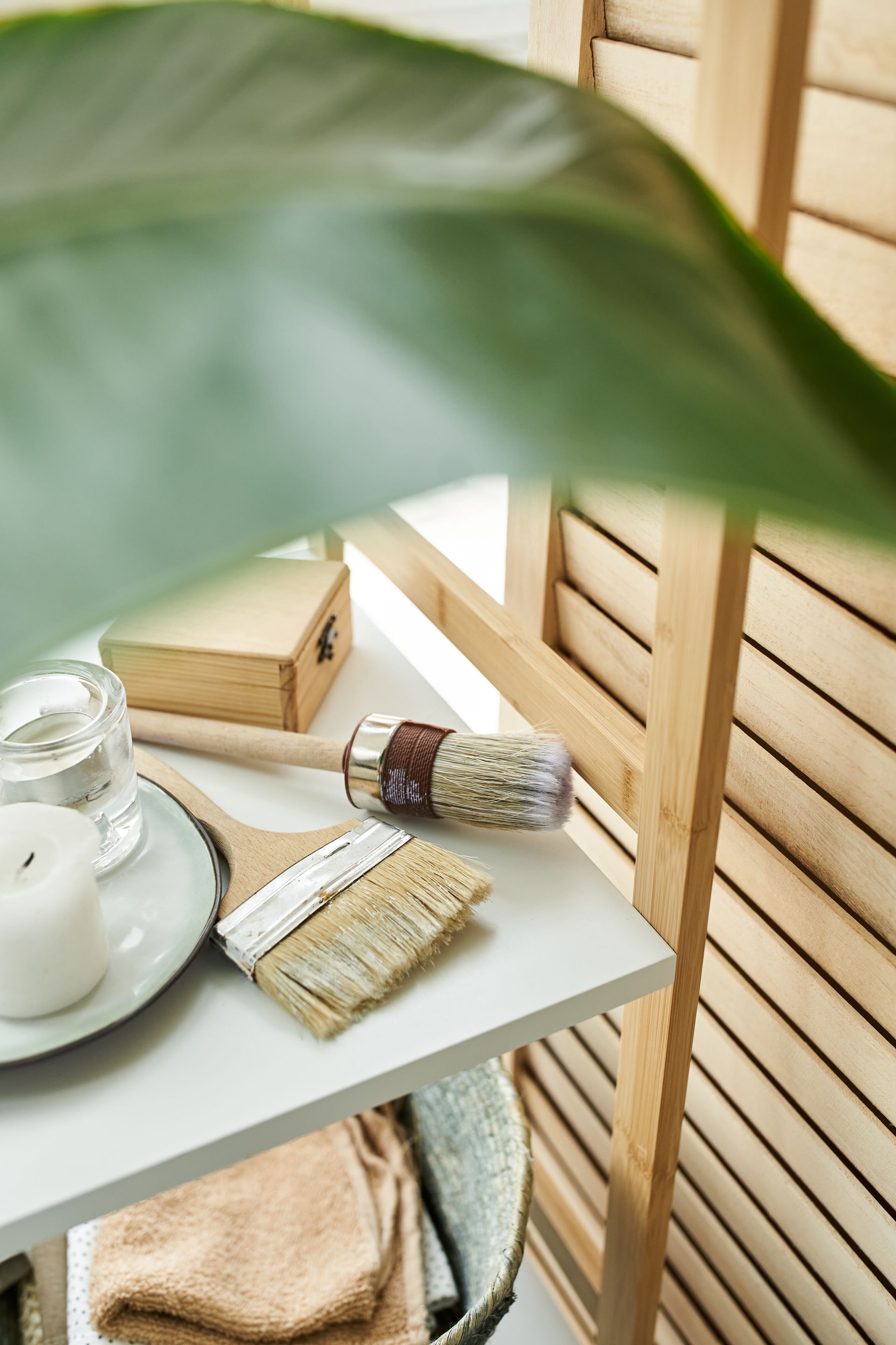 Sage green spa tray with candle, rolled towels, and bath accessories beside a wooden slatted wall Sage green spa tray with candle, rolled towels, and bath accessories beside a wooden slatted wall