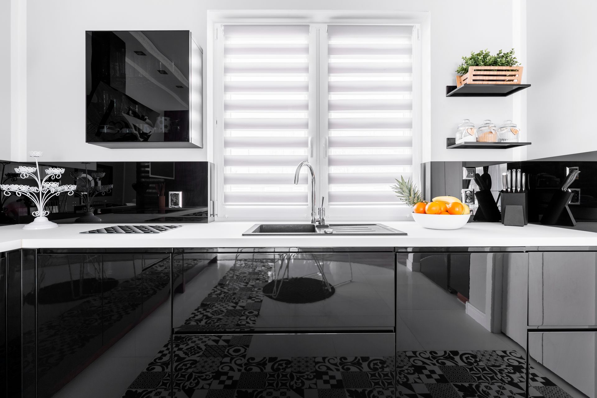 Modern black-and-white kitchen with glossy cabinets, window above sink, and shelves with plants and fruit Modern black-and-white kitchen with glossy cabinets, window above sink, and shelves with plants and fruit