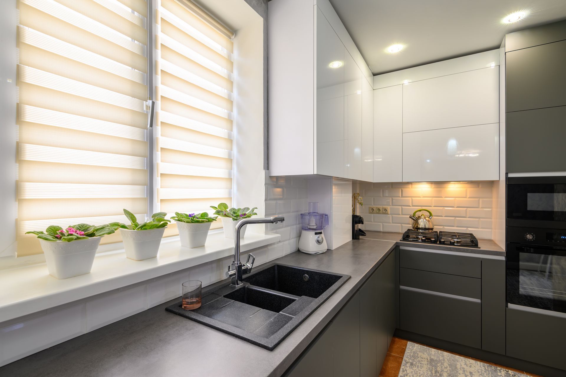 Modern kitchen with black counters, white cabinets, sink by window, and potted plants