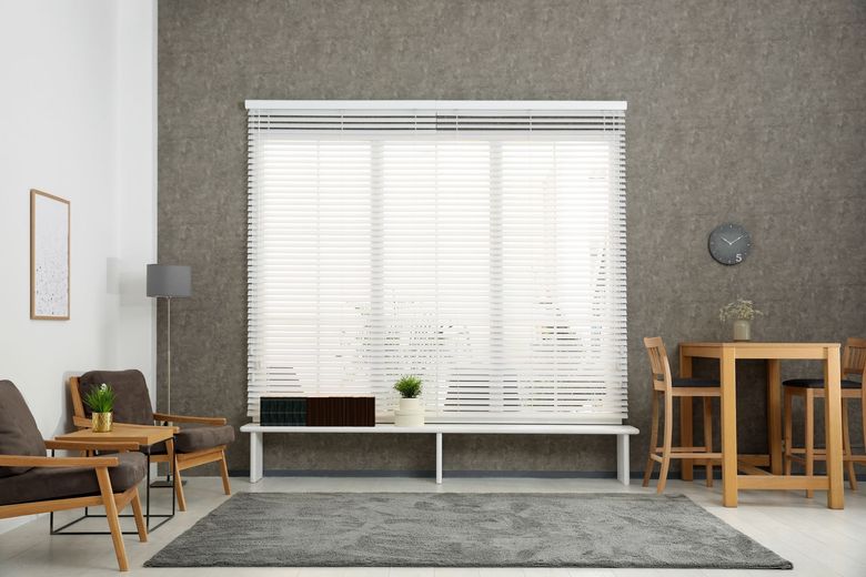 Modern living room with large window, gray walls, sofa, chairs, floor lamp, and small dining table Modern living room with large window, gray walls, sofa, chairs, floor lamp, and small dining table