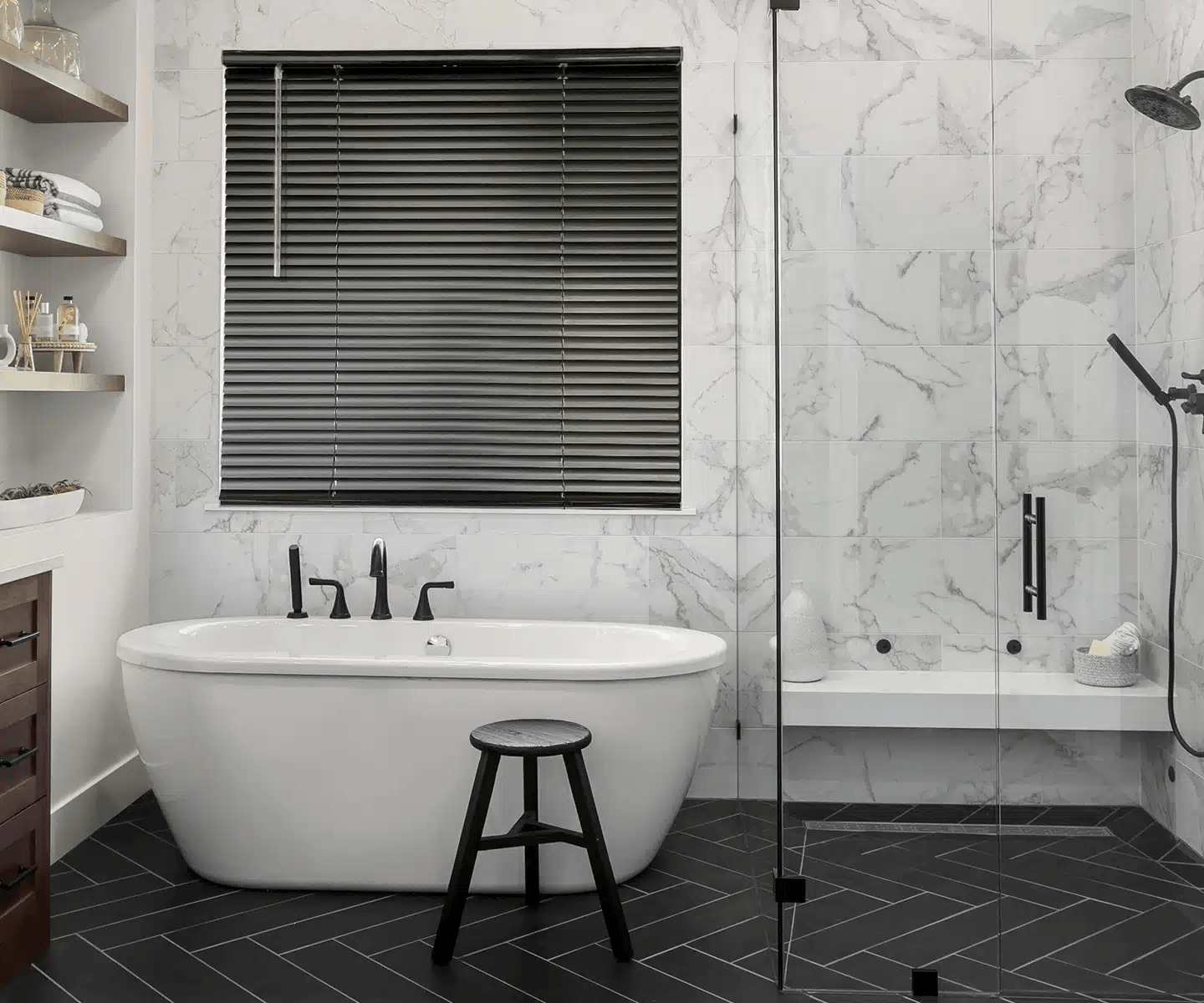 Modern bathroom with freestanding tub, glass shower, black floor, and marble tile walls