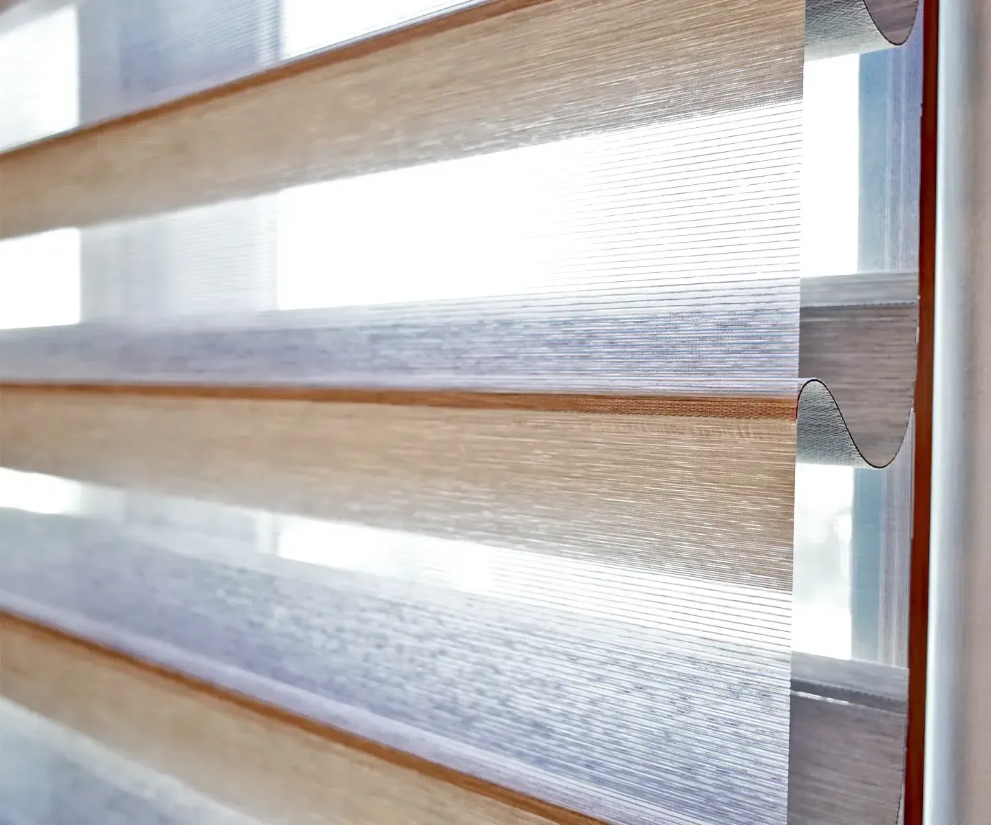 Close-up of translucent horizontal window blinds with light wood trim and daylight filtering through