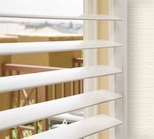 White window blinds partly open, showing a bright outdoor view through a window. White window blinds partly open, showing a bright outdoor view through a window.