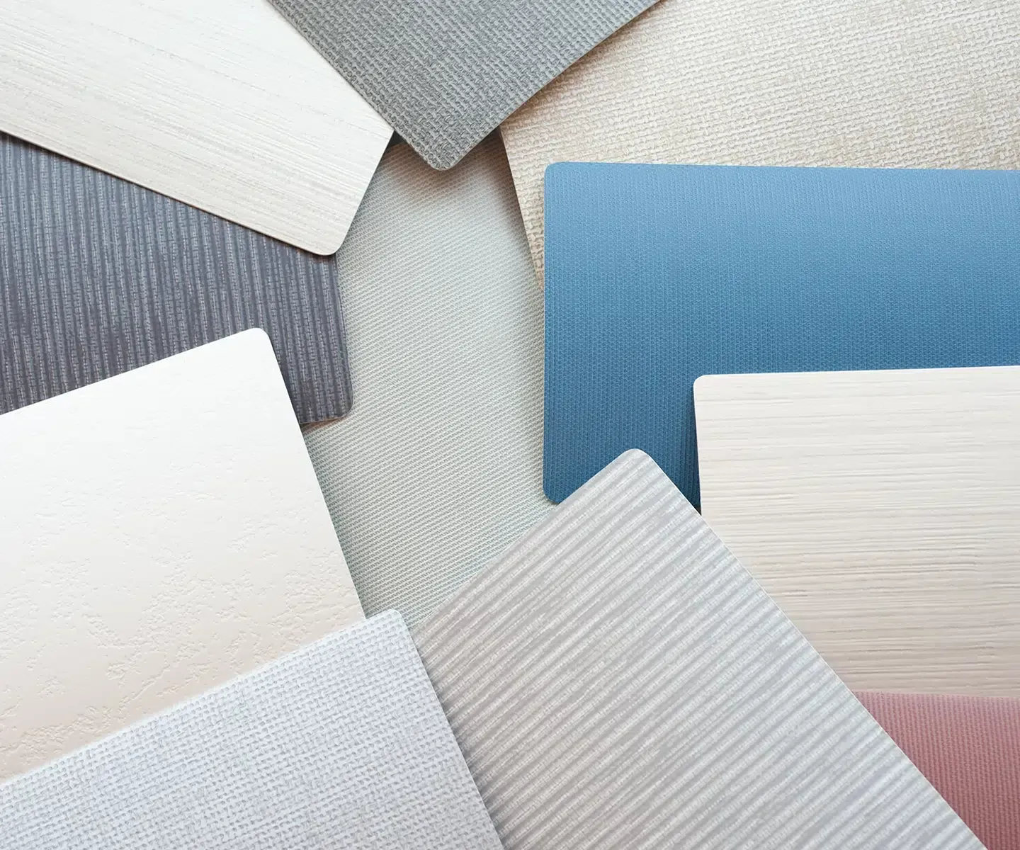 Assorted textured paper swatches in white, gray, and blue overlapping on a light background