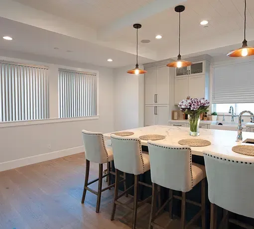 Modern kitchen with a large island, pendant lights, and a dining area with tall chairs Modern kitchen with a large island, pendant lights, and a dining area with tall chairs