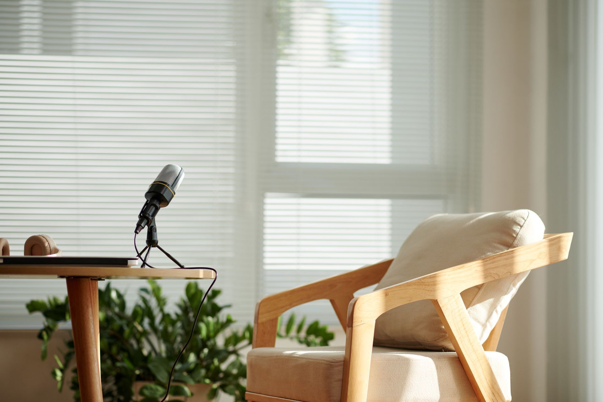 Microphone on a desk in a bright room with a beige chair and window blinds