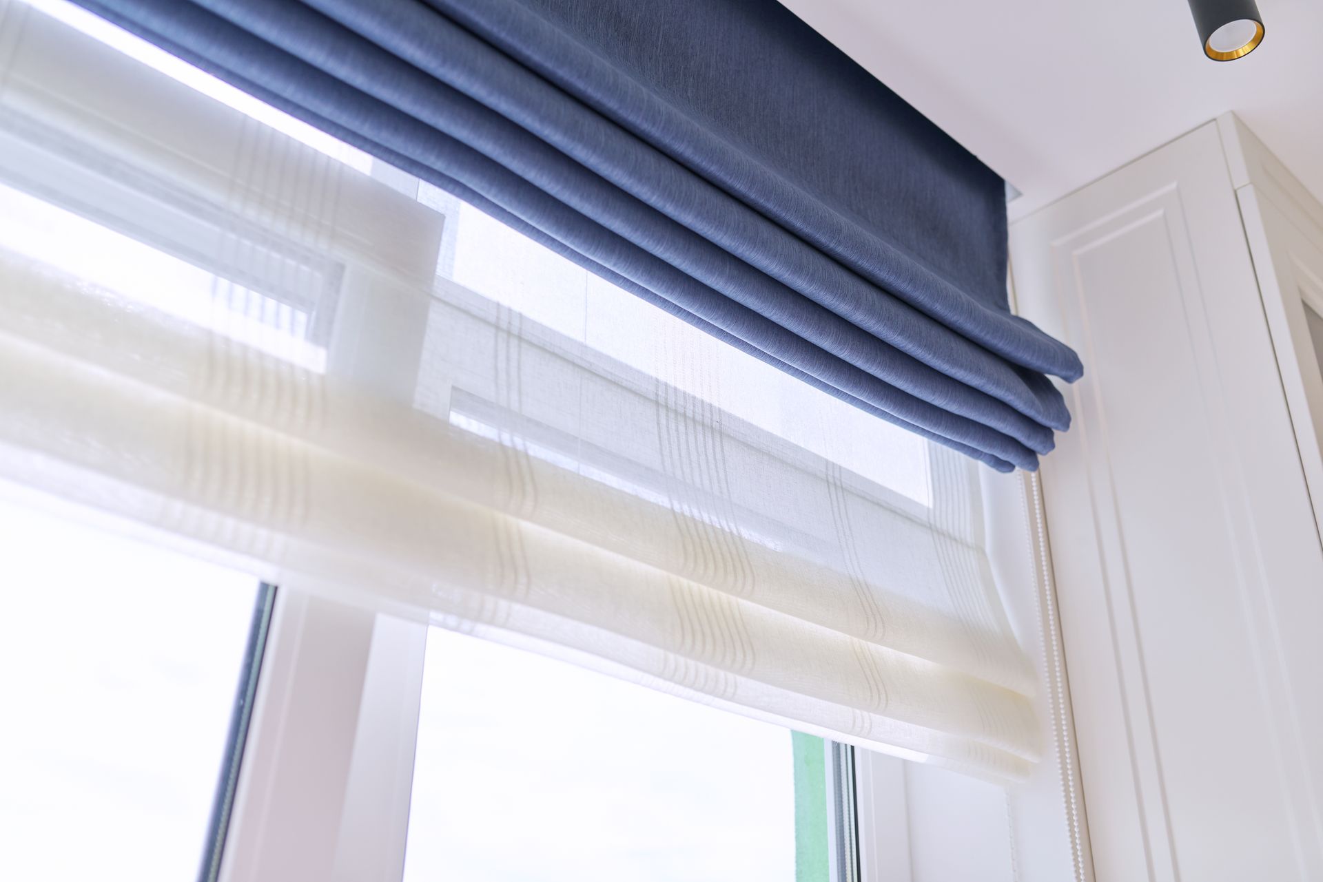 Blue and white window blinds filtering bright daylight Blue and white window blinds filtering bright daylight