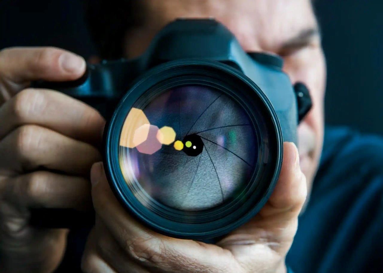 Persona che tiene in mano una macchina fotografica nera e guarda attraverso l'obiettivo.