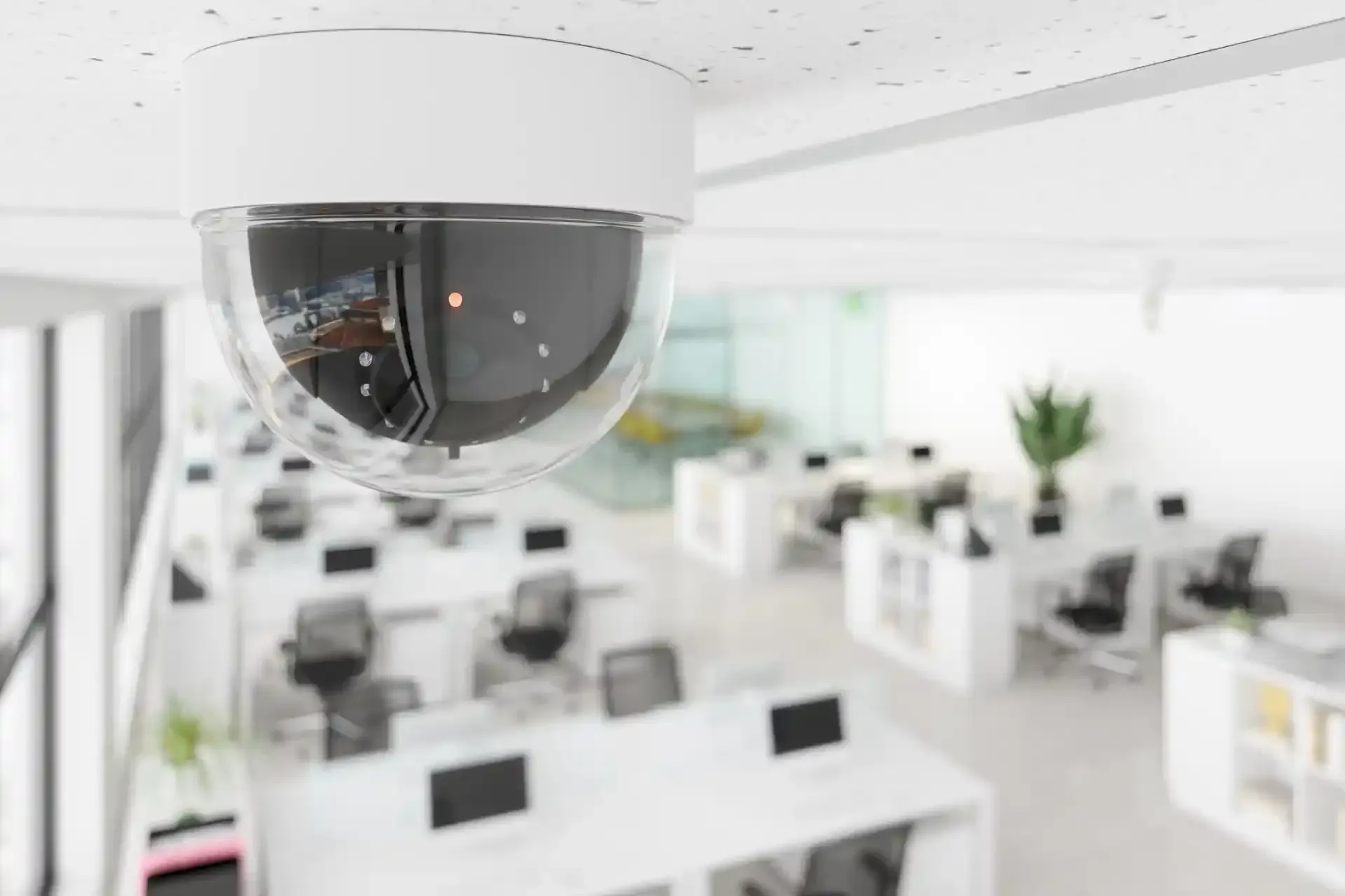 Telecamera di sicurezza in un ufficio con scrivanie e sedie bianche.