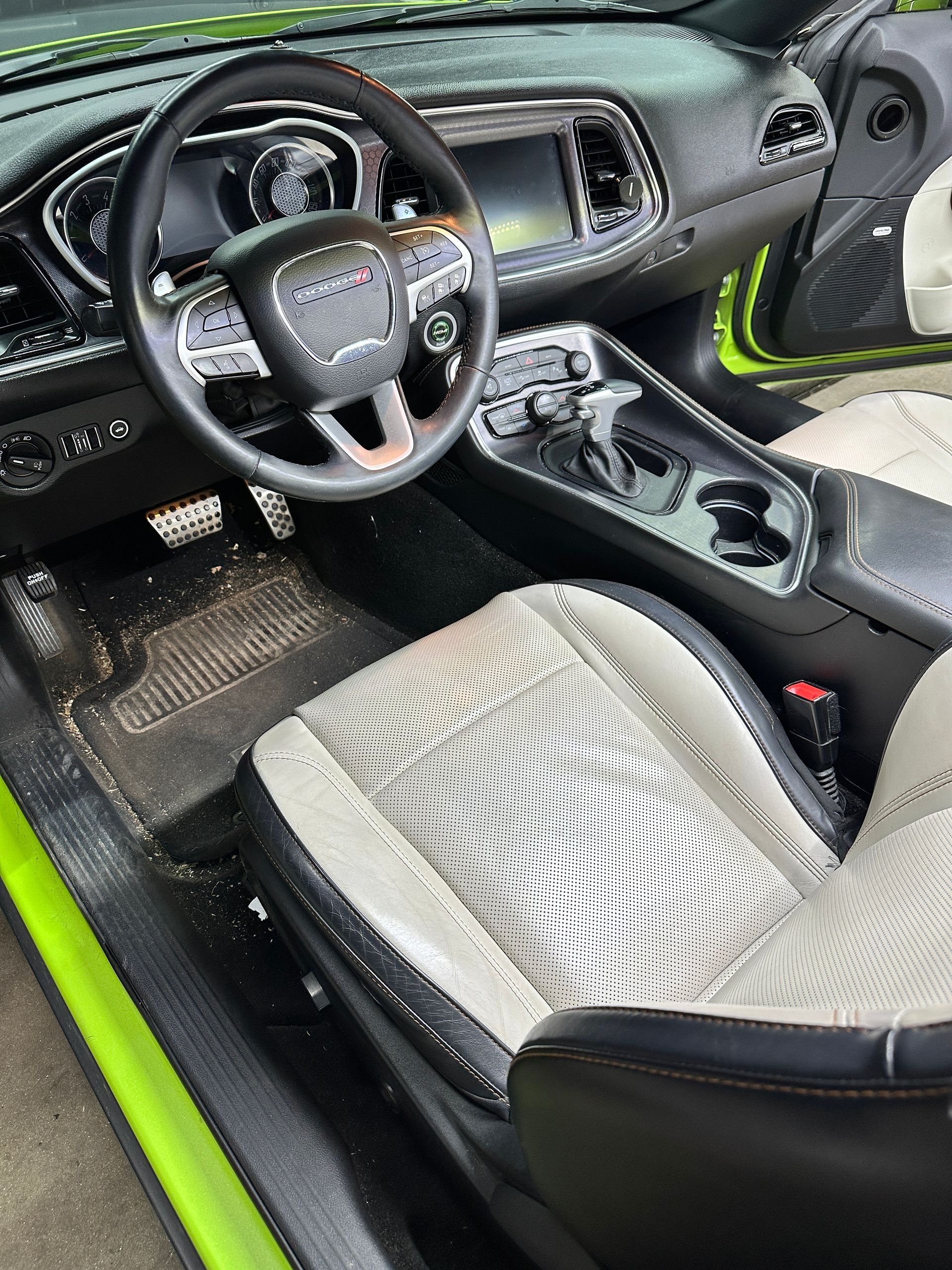 Driver's seat and dashboard of a lime green Dodge Challenger with black and white patterned bucket seats.