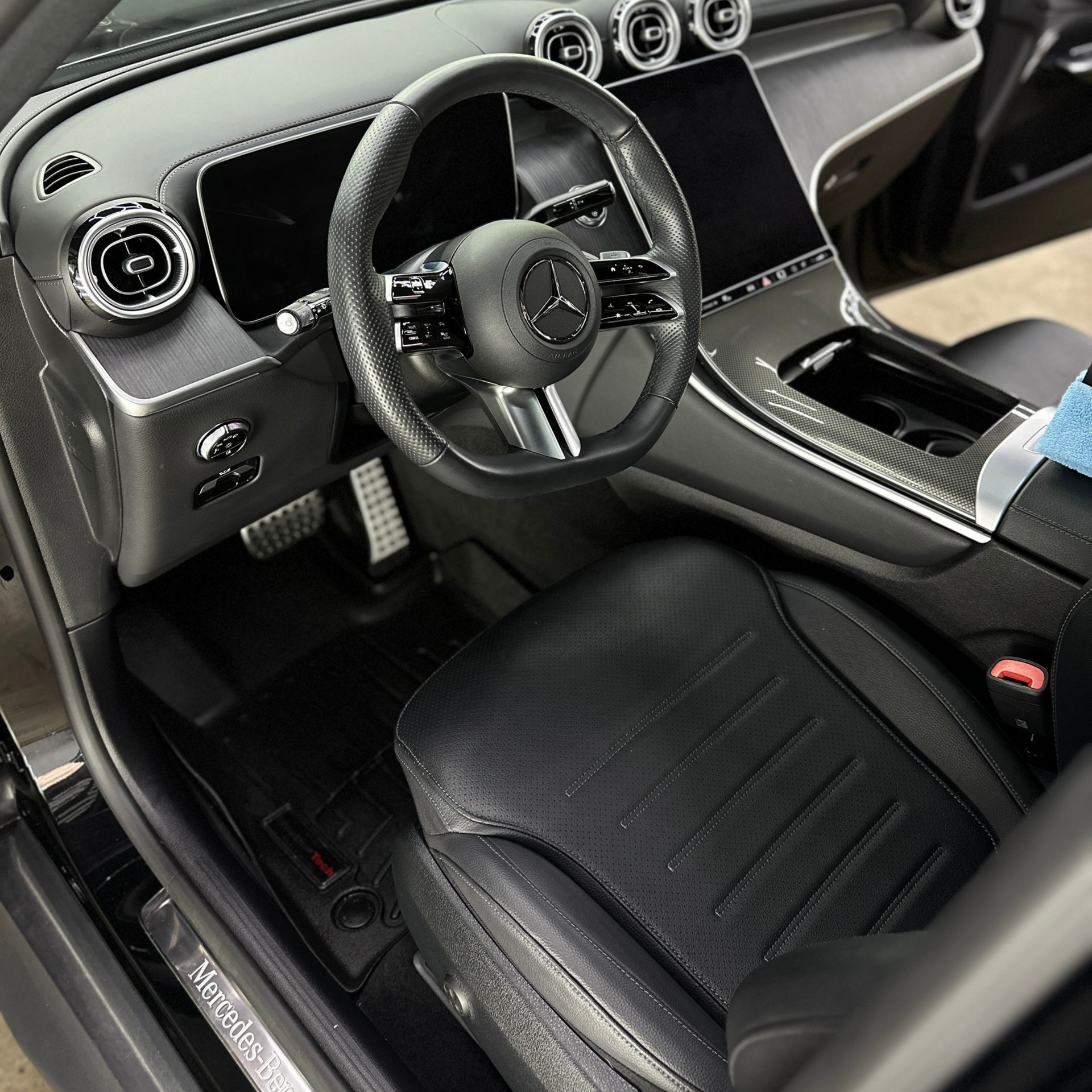 Interior view of a modern Mercedes-Benz vehicle, showing the leather driver's seat, black steering wheel, and dashboard.