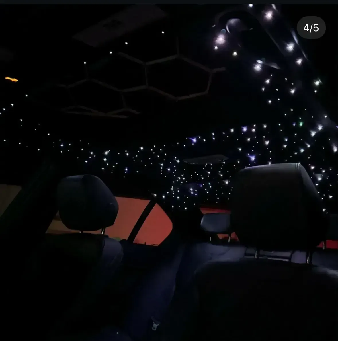 Interior view of a car ceiling featuring custom starlight fiber-optic lighting and an integrated honeycomb LED design.