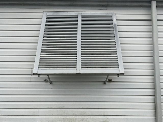 White louvered shutter on a gray-sided house wall