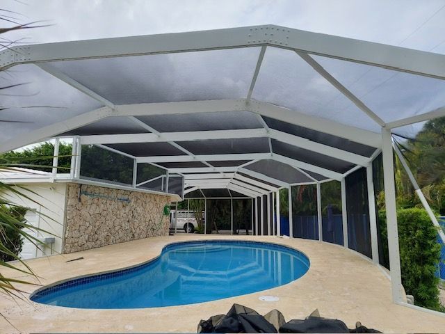 Covered backyard pool with blue water under a white screened enclosure