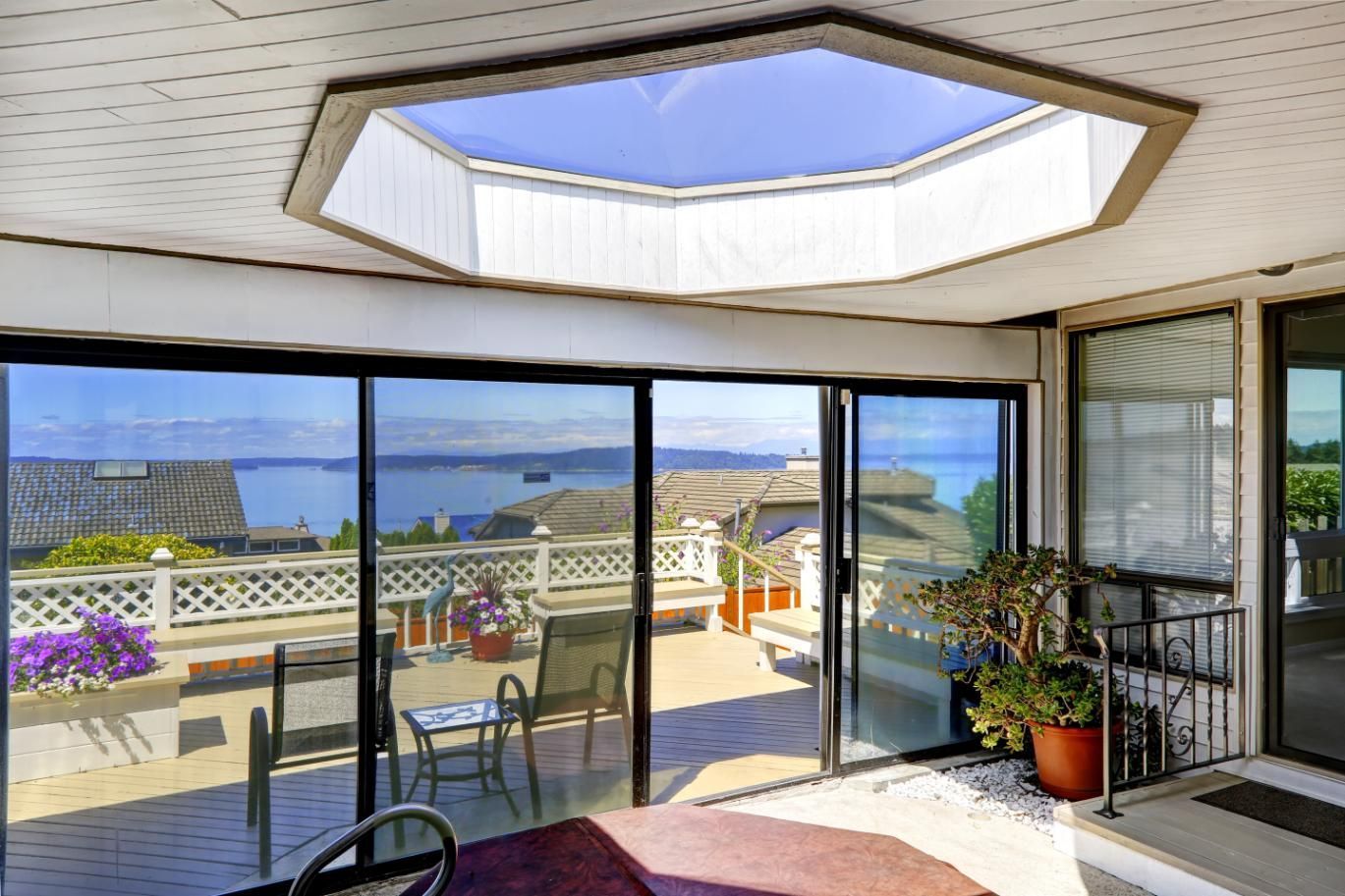 Sunlit room with octagonal skylight, sliding glass doors, and balcony view of the coast