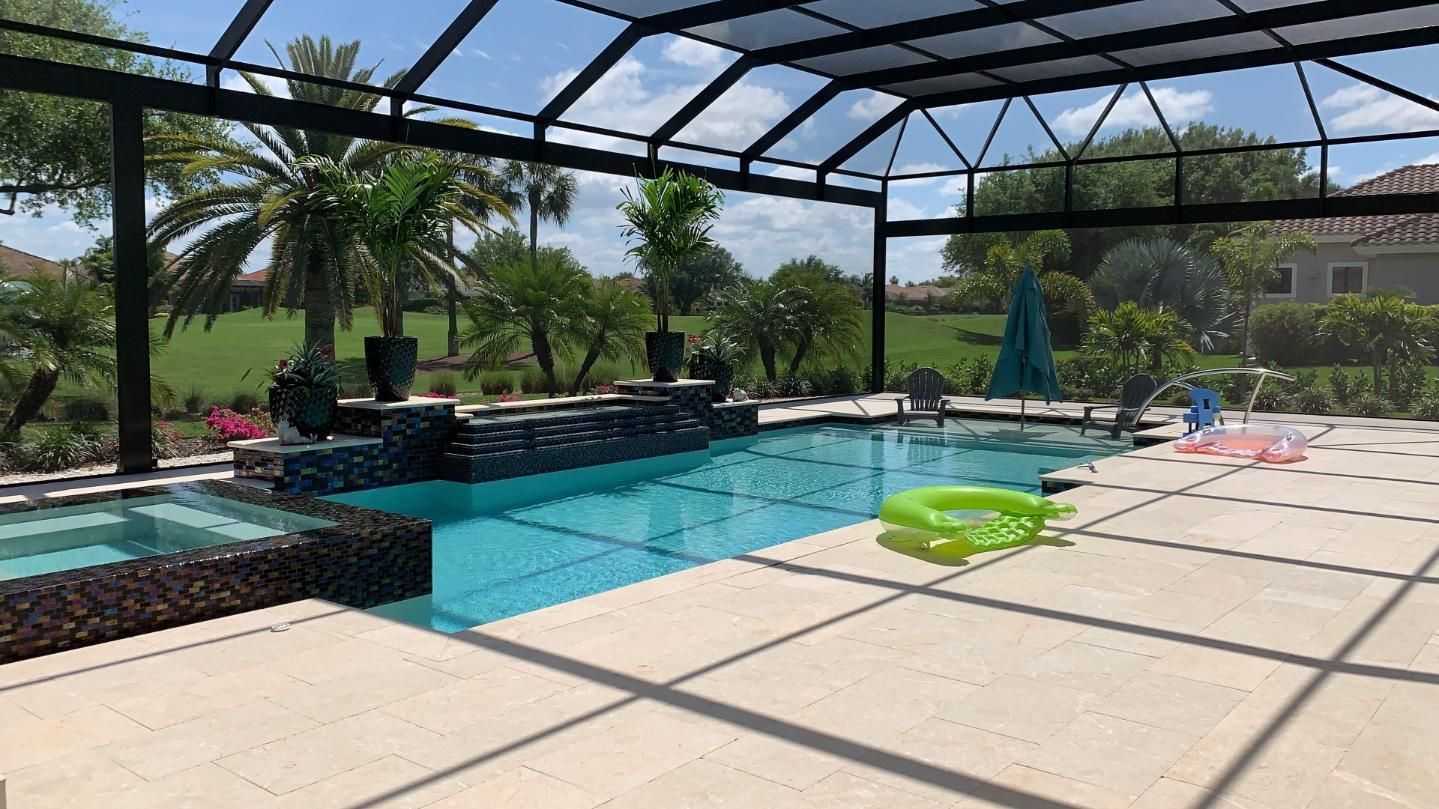 Covered outdoor pool with turquoise water, lounge chairs, palm trees, and a sunny patio area