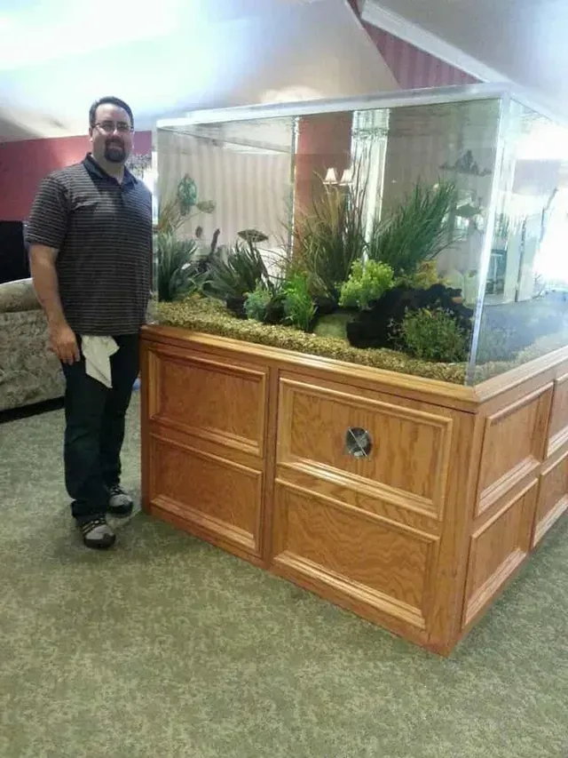 A man is standing in front of a large aquarium.