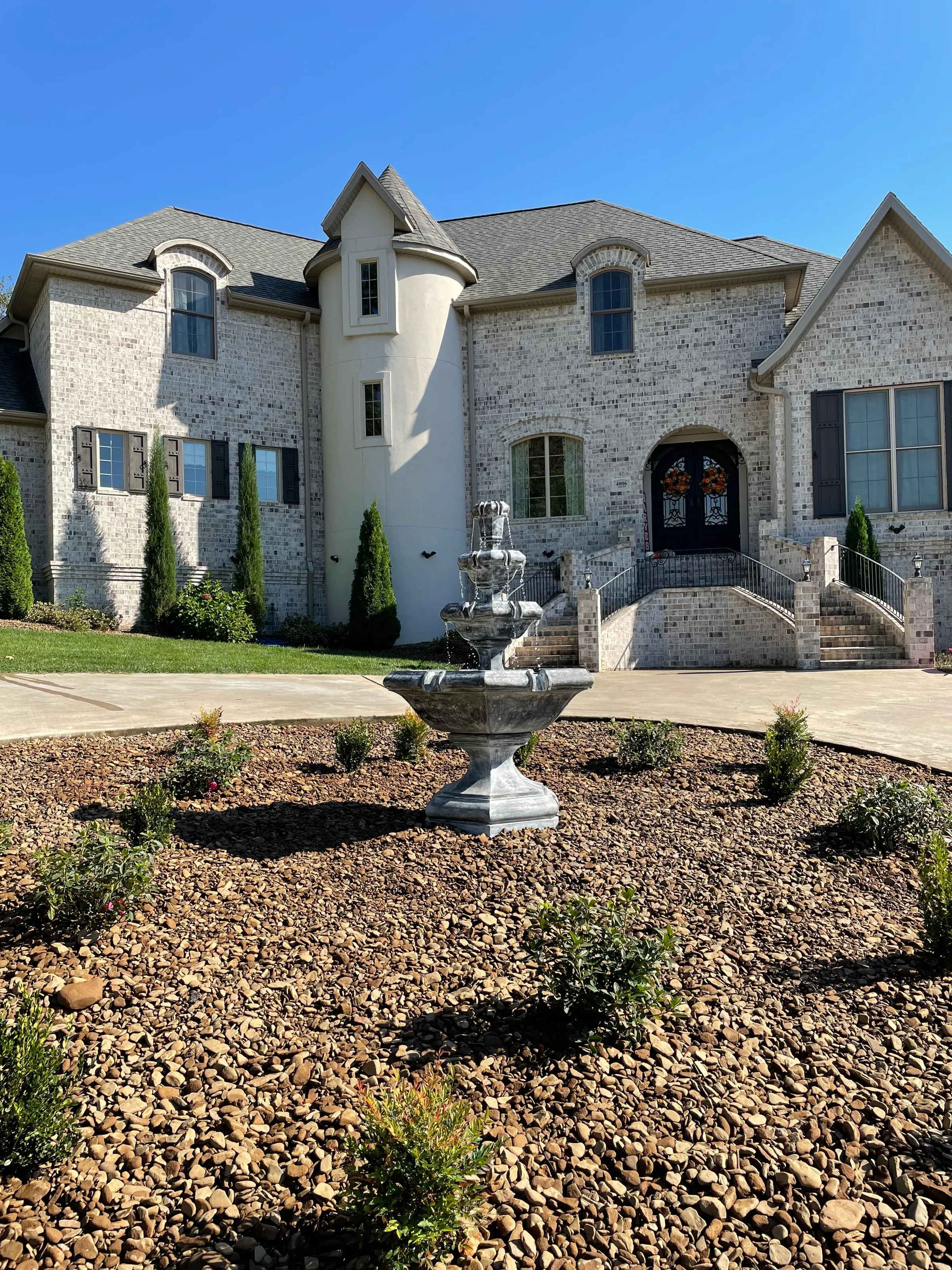 Elegant stone house with a fountain in a circular garden.