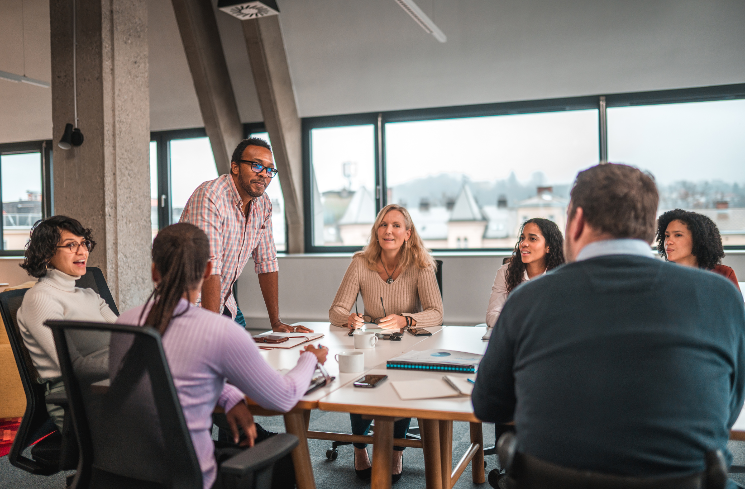 A group of people are sitting around a table having a meeting.