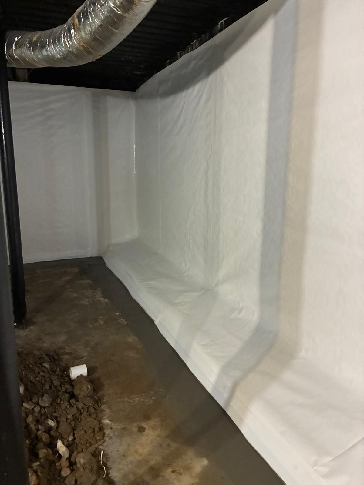 White-lined crawlspace under a house with exposed ducting and a dirt floor.