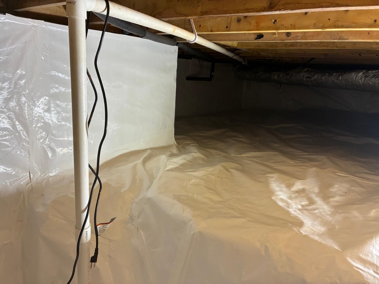 Crawlspace under house with plastic vapor barrier and hanging electrical wire