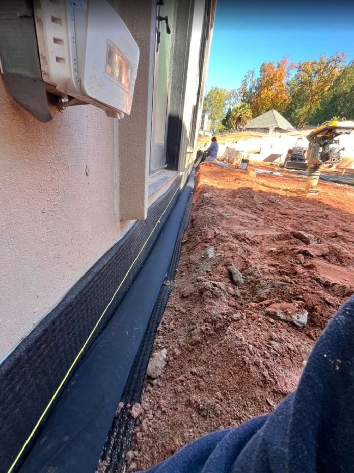 House exterior with foundation wrap and muddy construction site beside the wall
