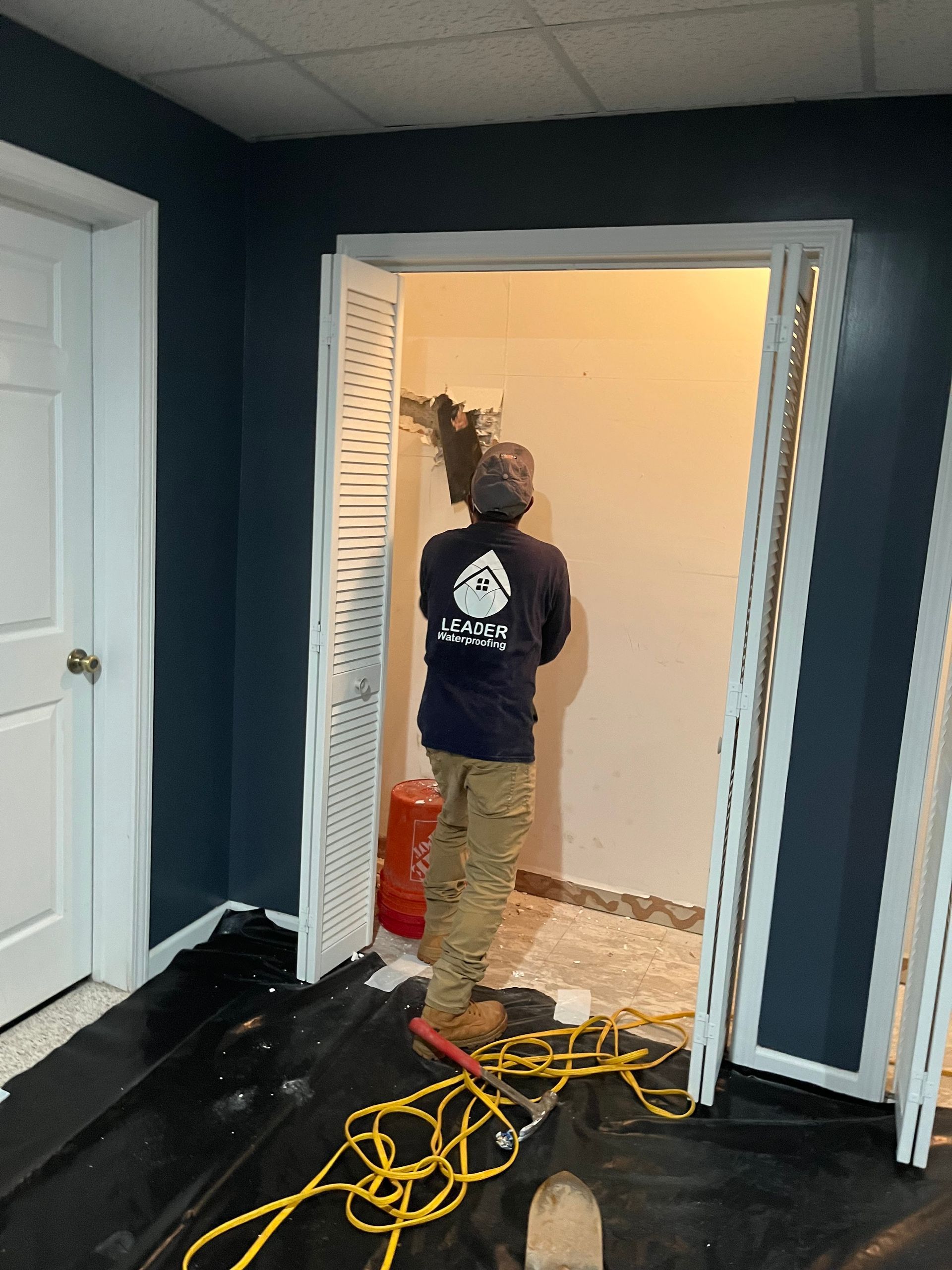 Person standing in a doorway with tools and extension cords on the floor