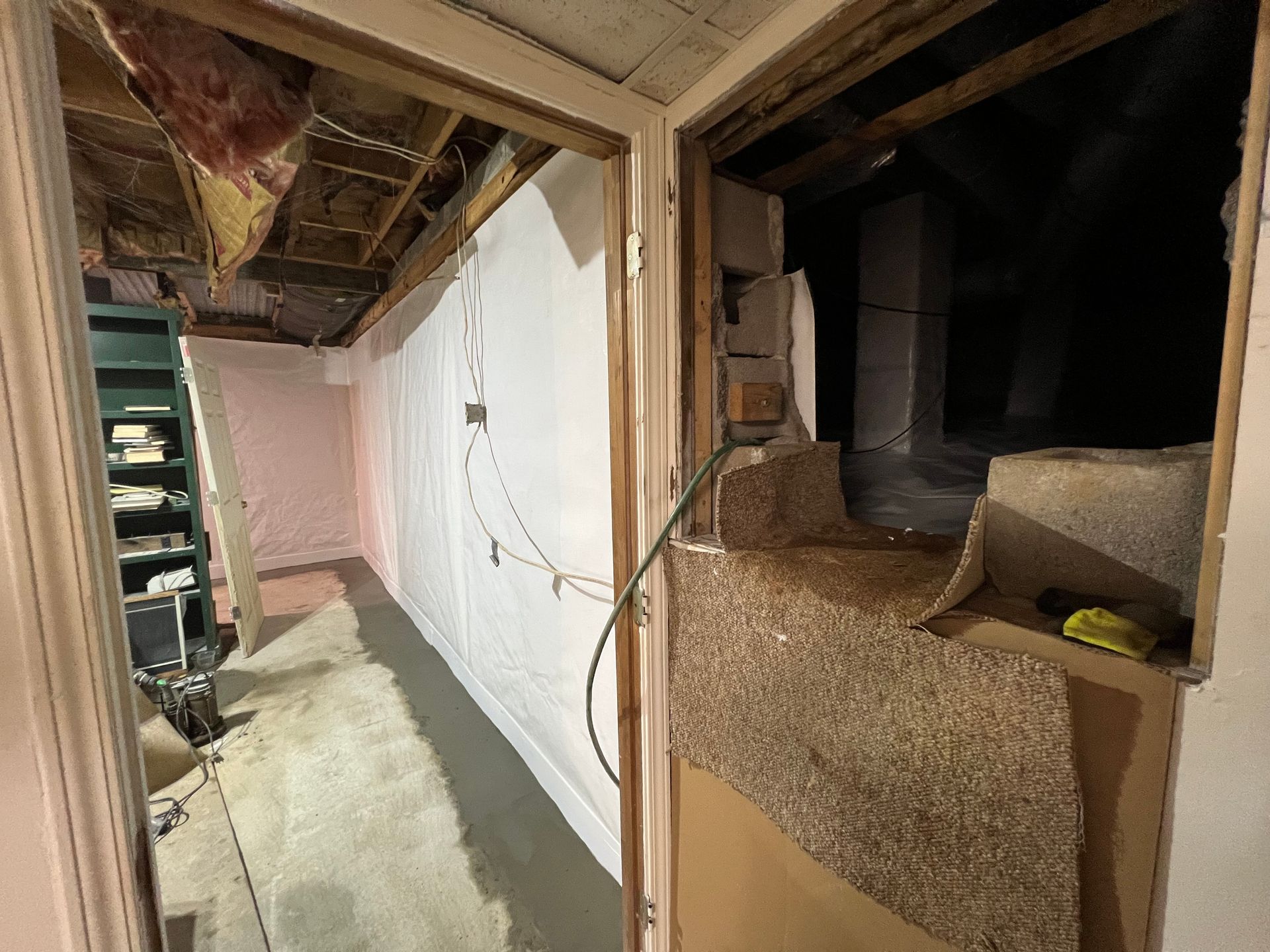 Damaged interior hallway with exposed ceiling, broken wall opening, and debris
